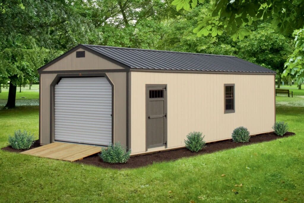 Beige shed with brown doors and roof. White garage door with wooden ramp. Shed sits in grass field with trees