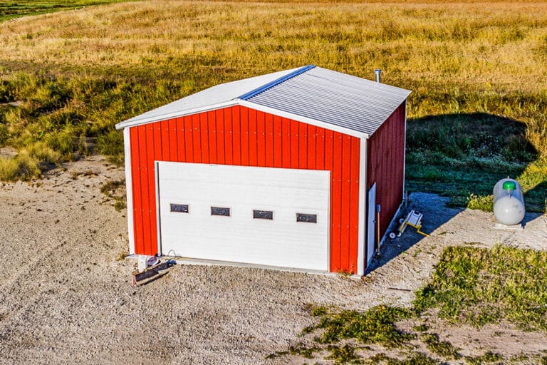 Red Northedge Steel metal garage with white overhead door in rural setting